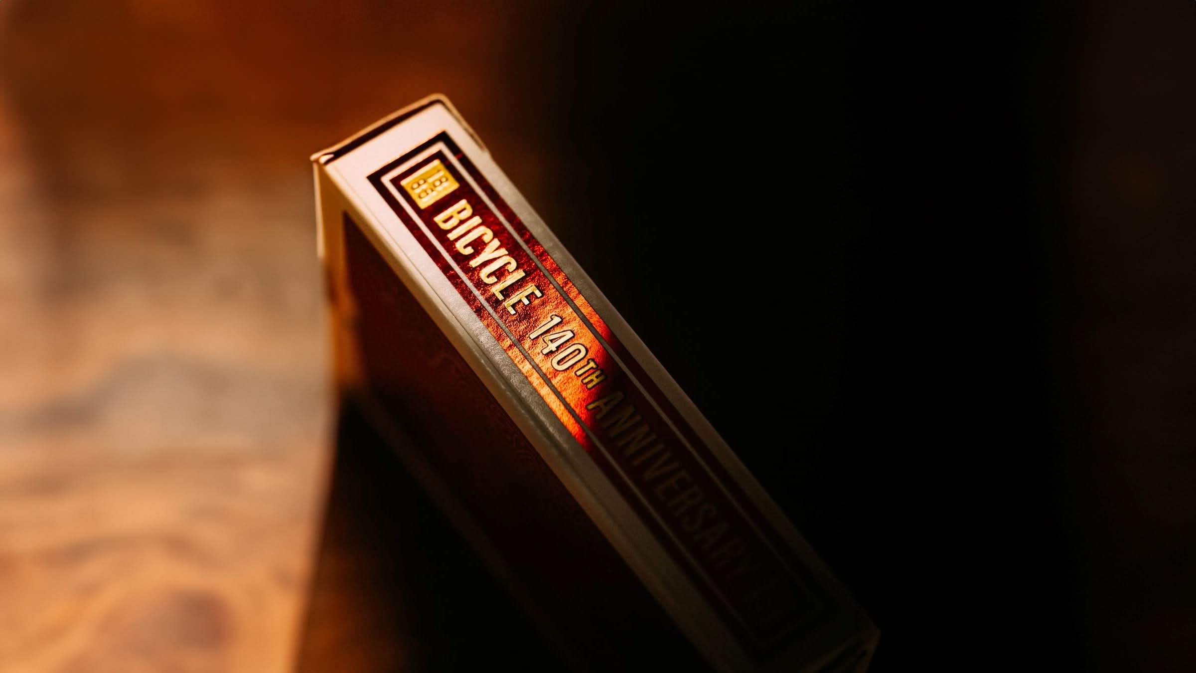 Close-up of the Bicycle 140th Anniversary Playing Cards deck, featuring elegant foil accents on the side of the tuck box. A must-have collector's edition for card enthusiasts, magicians, and Bicycle deck fans