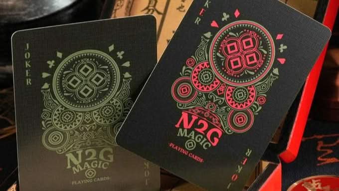 Black coinpix playing cards with red and green designs on a vintage-style box