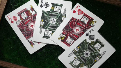 Four playing cards from the n2g coipix deck featuring kings from different suits on a green surface.