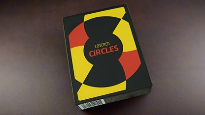 Close-up view of the Chris Cards Covered Circle (Standard Edition) Playing Cards box. The design features bold geometric patterns in red, yellow, and black, with the title 'Covered Circles' prominently displayed in the center.