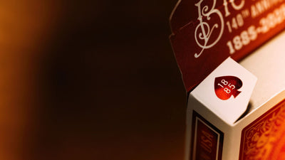 Close-up of a Bicycle 140th Anniversary playing card tuck box flaps with 1885 luxurious red foil detailing on a deep red background. Available at 52Kards for collectors, magicians, and card enthusiasts.