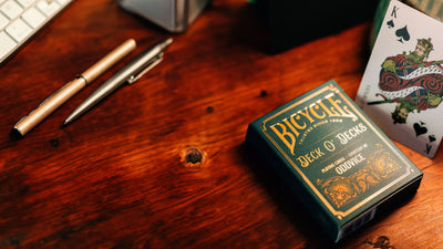 Bicycle Oddvice tuck box beside two pens and a partially visible King of Spades