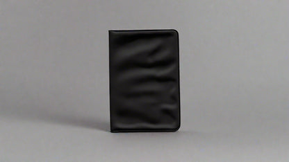 Image of a plain black wallet or cardholder with a smooth, matte finish. The rectangular object is photographed against a simple background.